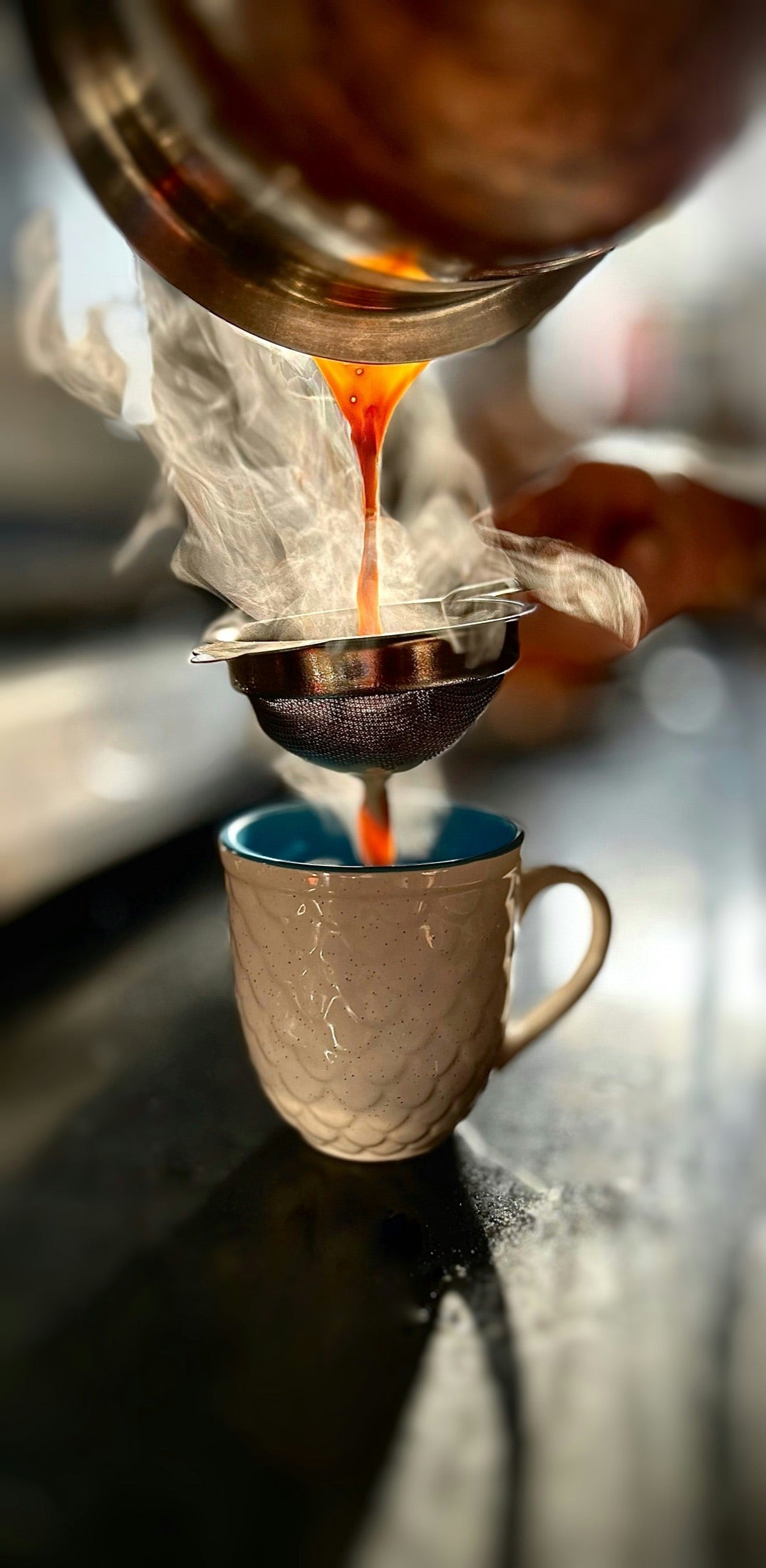Hot doodh patti chai being strained into a mug